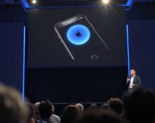 Apple WWDC 2026 keynote stage with Siri AI demo on screen and presenter holding iPhone