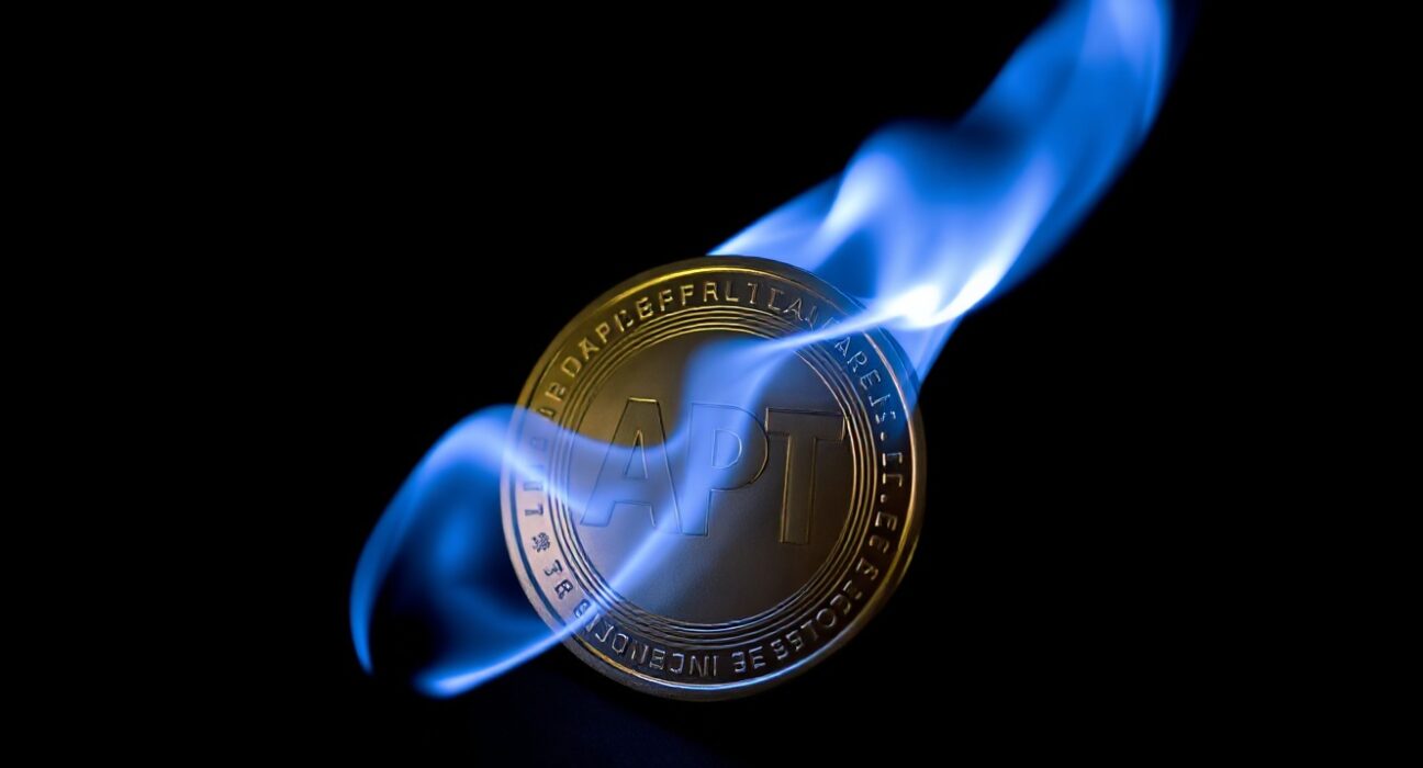 Aptos APT token being burned in a controlled flame against a dark background.