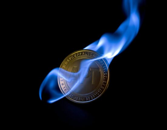 Aptos APT token being burned in a controlled flame against a dark background.