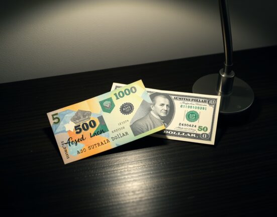 Australian Dollar and US Dollar banknotes on a dark surface, representing AUD/USD currency pair consolidation.