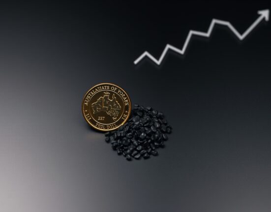 Australian dollar coin with iron ore pellets on dark surface representing commodity-driven currency