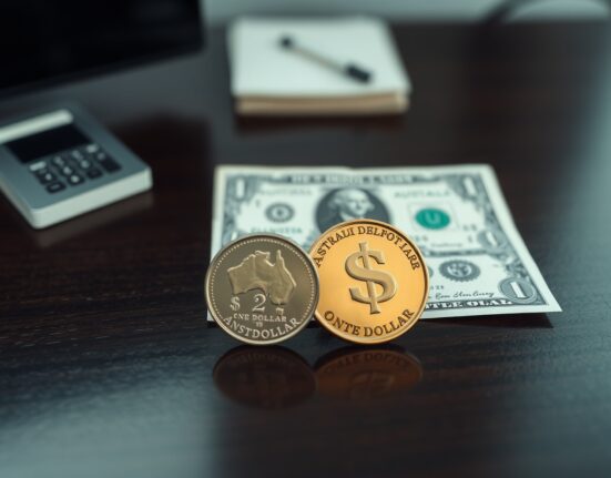 Australian coin and US dollar bill on a dark surface, representing AUD/USD currency pair.