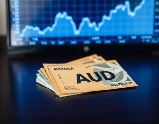 Australian Dollar banknotes with a blurred financial chart in the background indicating positive economic data.
