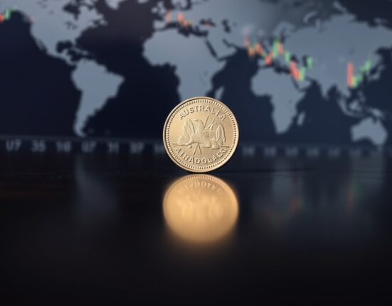Australian dollar coin on wooden surface with financial chart background