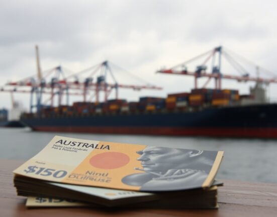 Australian dollar banknotes with blurred shipping port background symbolizing trade and currency pressure
