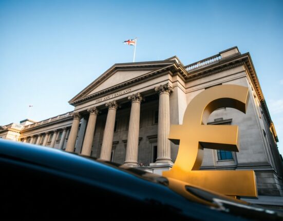 Bank of England building in London with a British pound symbol in the foreground.