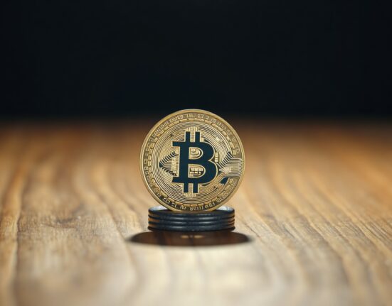 Bitcoin coin on edge of table in dark, moody lighting symbolizing market uncertainty