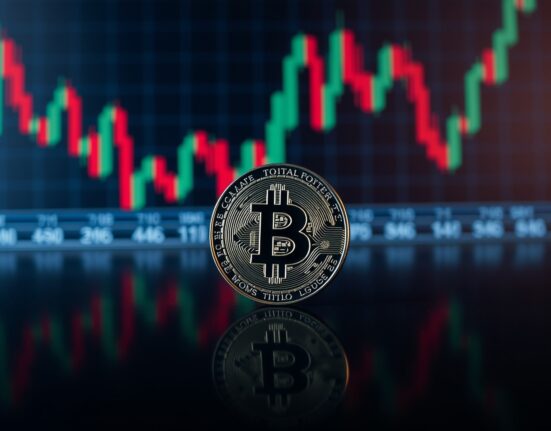 Bitcoin coin on reflective surface with blurred trading chart background