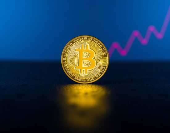 Bitcoin coin with a faint red declining graph in the background, representing bearish market signals