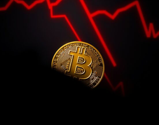 Bitcoin coin with downward-trending red chart lines representing price drop amid market sell-off