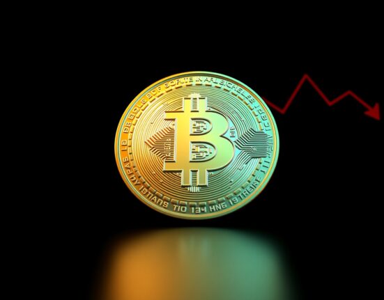 Bitcoin coin with downward trend indicators on dark background representing price drop below $77,000