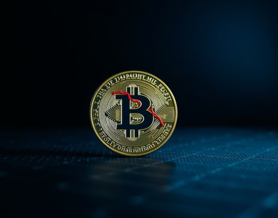 Bitcoin coin with a reflection of a red downward chart, representing a potential market bottom and liquidation risk.