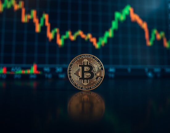 Bitcoin coin on reflective surface with green chart background