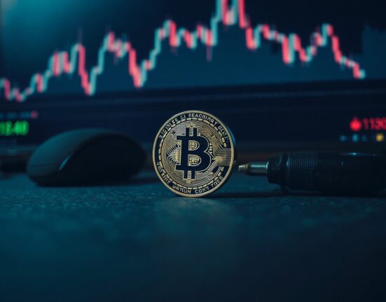Bitcoin coin in foreground with blurred stock chart background, symbolizing market analysis.