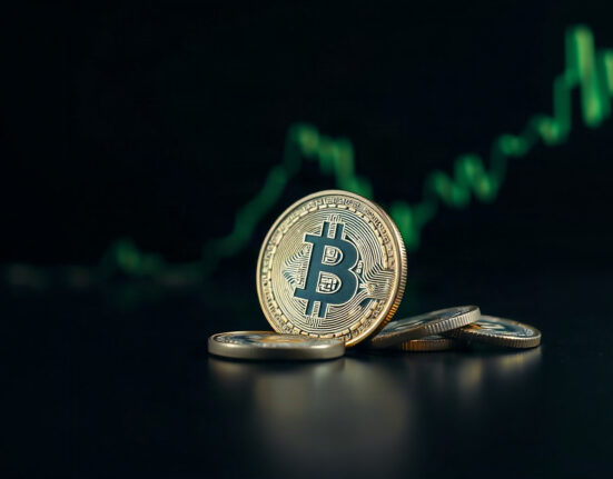 Bitcoin coin on reflective surface with green chart in background symbolizing price rebound