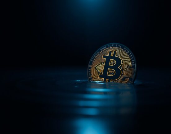 Bitcoin coin partially submerged in dark water, symbolizing unrealized losses in the crypto market.