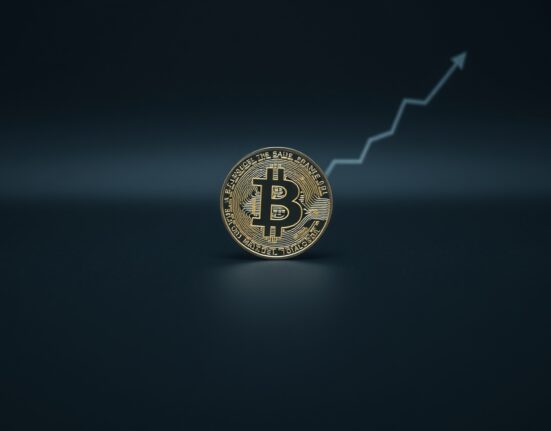 Bitcoin coin on dark surface with subtle upward trend graph in background representing long-term holder accumulation