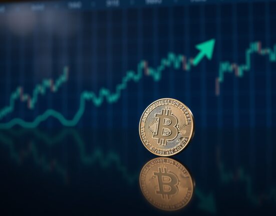 Bitcoin coin on reflective surface with subtle green upward arrow representing market stability