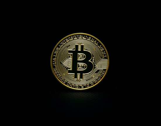 Bitcoin coin on dark surface, symbolizing critical price resistance level analysis.