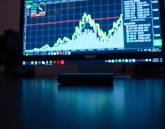 Bitcoin hardware wallet on desk with chart spike in background