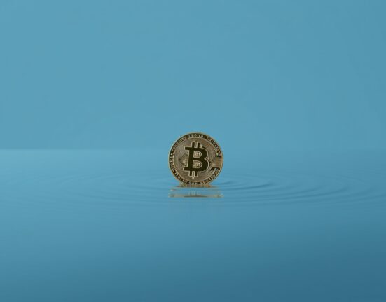Bitcoin coin resting on calm water, representing low market volatility
