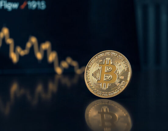 Bitcoin coin on a reflective surface with a subtle upward chart in the background, symbolizing market recovery.