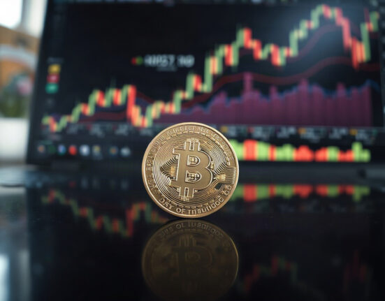 Bitcoin coin on reflective surface with financial charts in background, symbolizing renewed bullish momentum