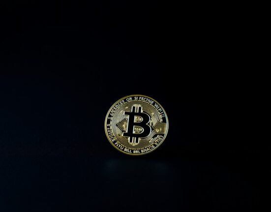 Bitcoin coin with a red shadow suggesting a short-term market top