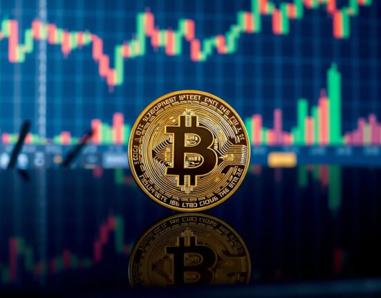 Bitcoin coin in foreground with blurred financial charts in background, representing market analysis.
