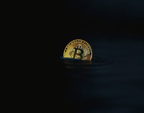Bitcoin coin partially submerged in dark water representing supply in loss