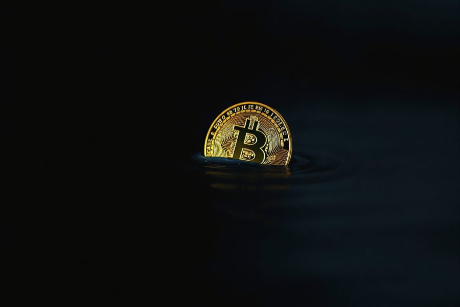Bitcoin coin partially submerged in dark water representing supply in loss