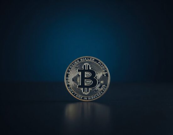 Bitcoin coin on a dark reflective surface, symbolizing a price milestone above $65,000.