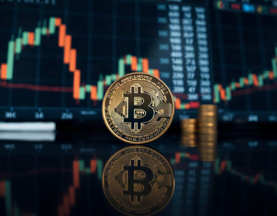 Bitcoin coin on reflective surface with blurred market chart in background