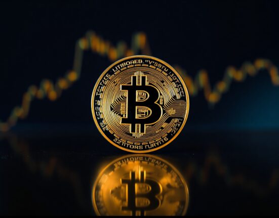 Bitcoin coin on reflective surface with subtle financial chart background