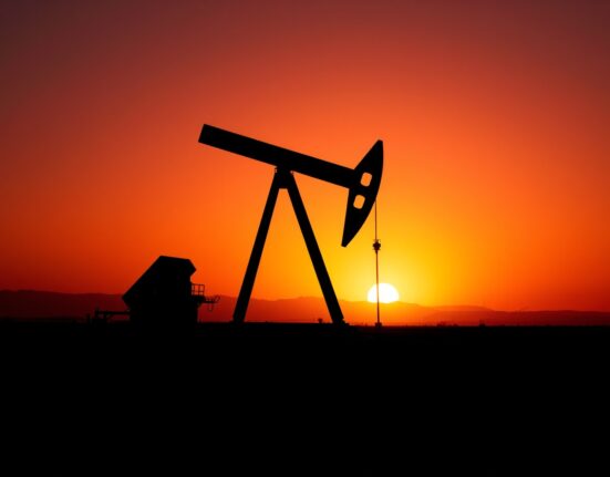 Oil pumpjack silhouetted against sunset sky, representing Brent crude market volatility and geopolitical risk