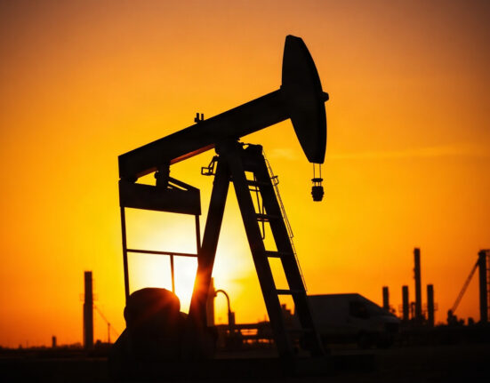 Crude oil pumpjack at sunset with refinery in background, representing supply risks.