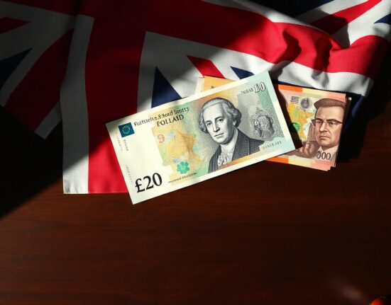 British Pound banknote with US Dollar and Euro notes in background on desk