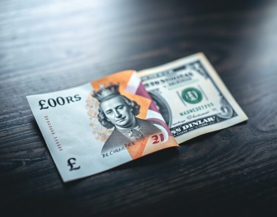 British Pound and US Dollar banknotes on a desk, representing GBP/USD forex trading analysis by UOB.