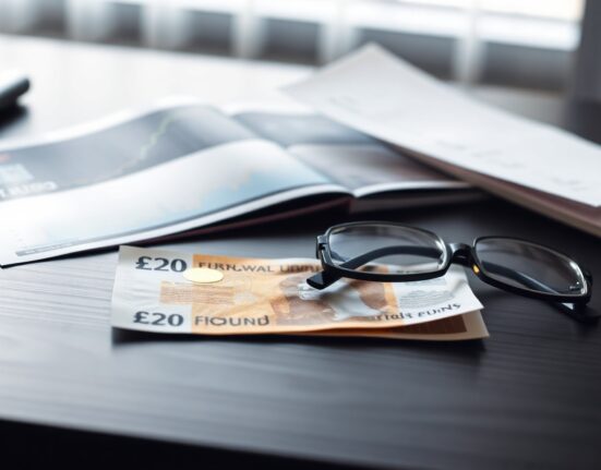 British Pound note and financial chart on desk, representing forex market and economic news.