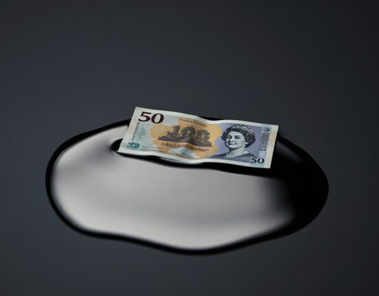 British Pound note partially submerged in crude oil illustrating inflation and energy price impact