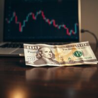 British Pound and US Dollar banknotes on a desk with a chart on a laptop, representing currency market movements.