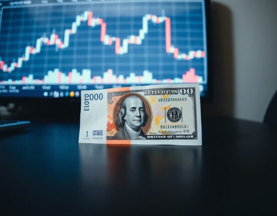 British Pound and US Dollar banknotes on a table with a financial chart in the background.