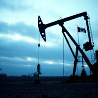 Canadian oil pumpjack in a dry field under an overcast sky, symbolizing economic fragility