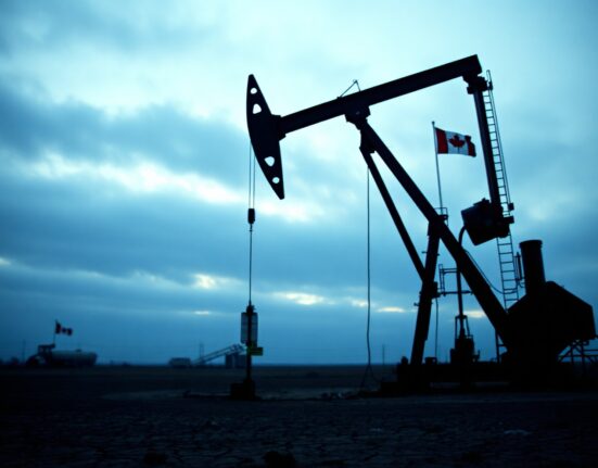 Canadian oil pumpjack in a dry field under an overcast sky, symbolizing economic fragility