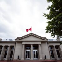 Bank of Canada building in Ottawa under overcast sky with Canadian flag