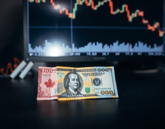 Canadian dollar and US dollar banknotes with a declining forex chart in background