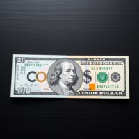Canadian and US dollar banknotes on a dark surface with a market graph overlay