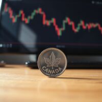 Canadian loonie coin on desk with economic chart in background