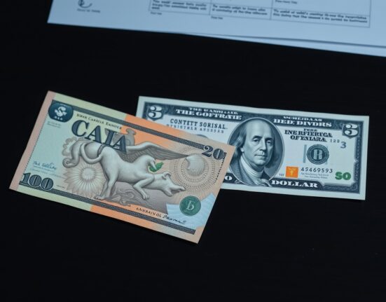 Canadian and US dollar banknotes on a desk representing currency market analysis and tariff impact.