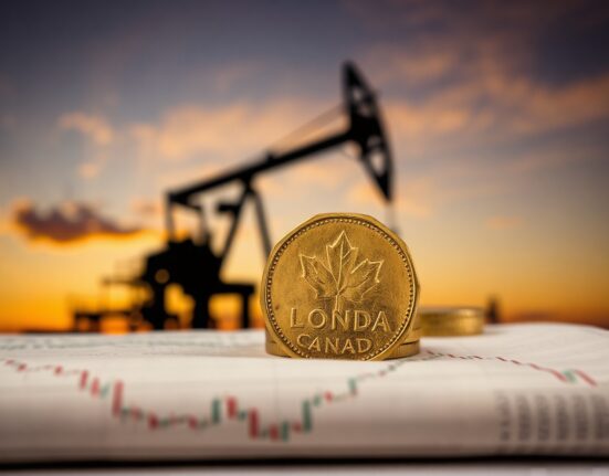 Canadian dollar coin on financial chart with oil rig background